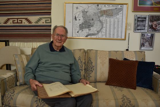 Ernest Glaser zeigt seine Schulzeugnisse aus Berlin. In seinem Arbeitszimmer hängt ein Stadtplan von Shanghai (Foto: Birgit Mair im September 2024)